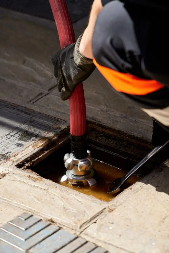 Plumber introducing jetting equipment through a drain.