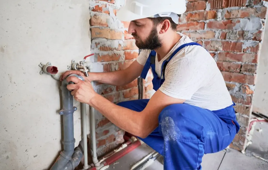 Plumber repairing pipes on a wall.