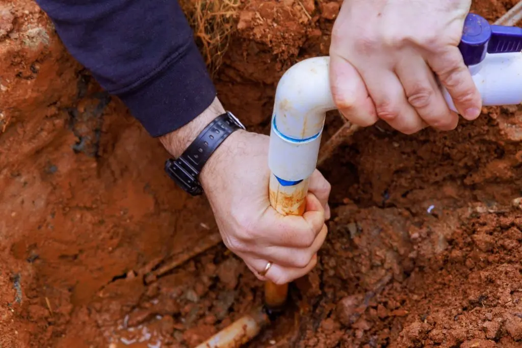 Plumber glueing two pipes together.