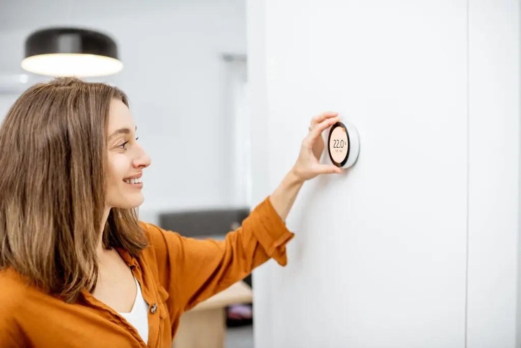 Woman adjusting the temperature in her new thermostat.