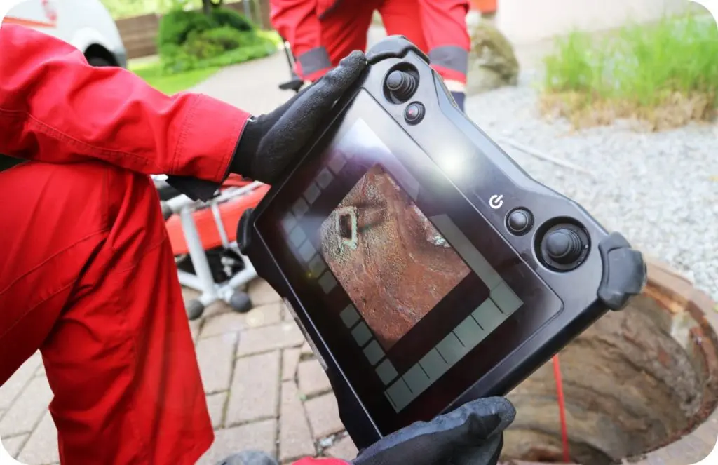 Two plumbers reviewing a drain camera inspection's footage.