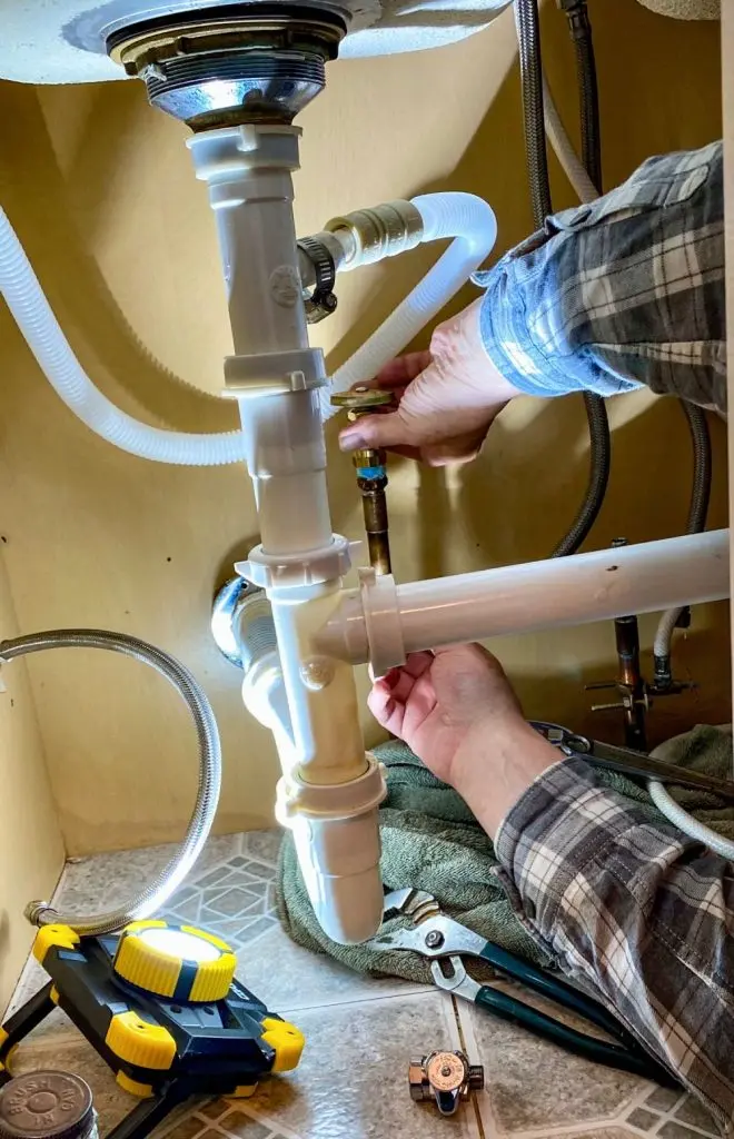 Plumber repairing pipes under a sink.