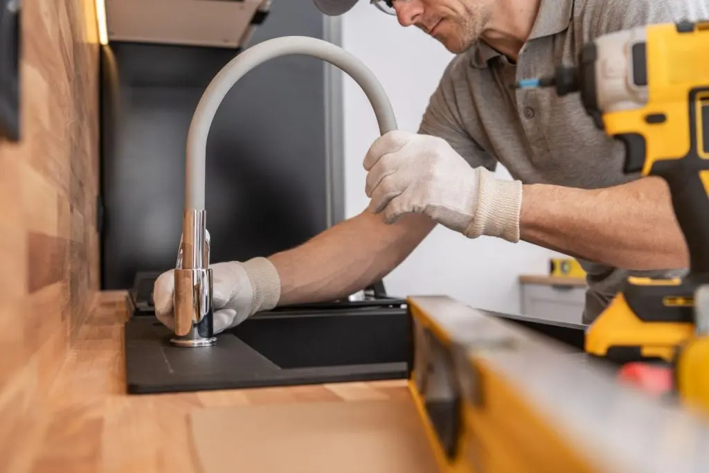 Plumber setting up a kitchen faucet.