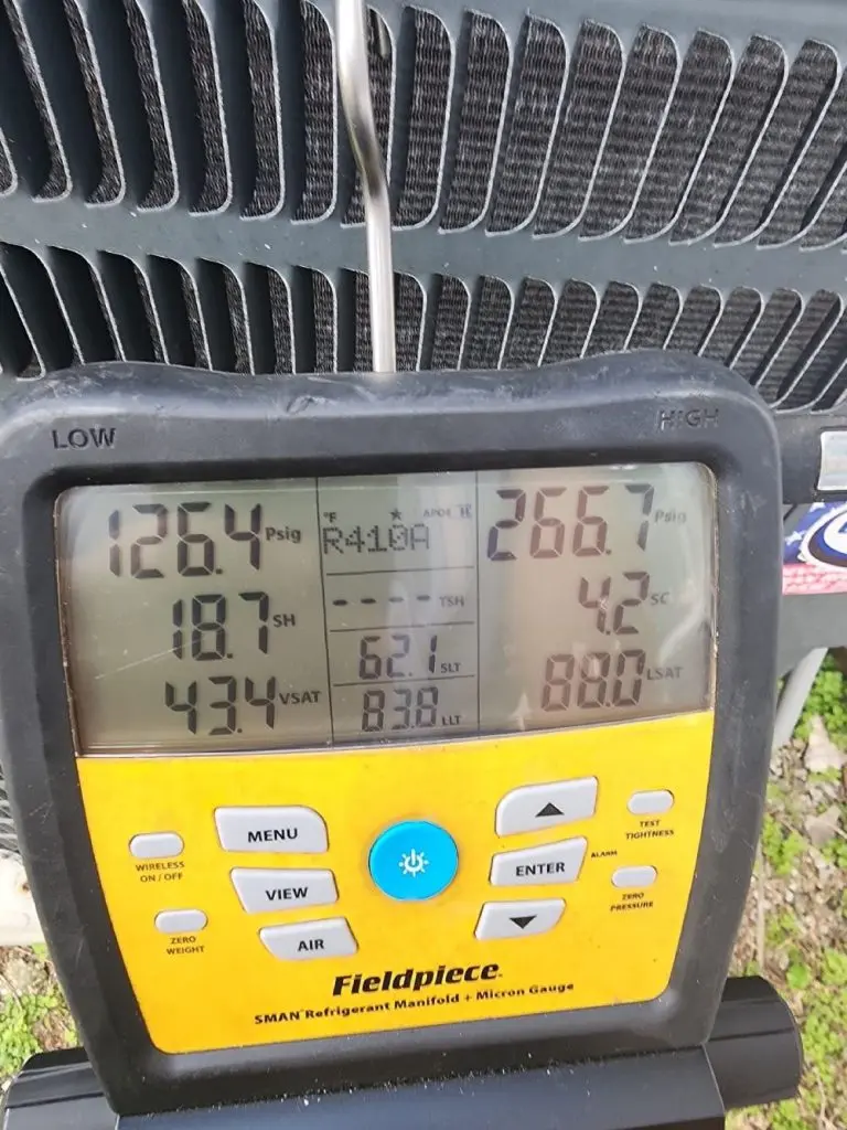Technician using refrigerant checking equipment on an AC.