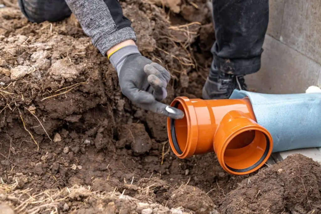 Plumber inspecting a pipe mid-repair.